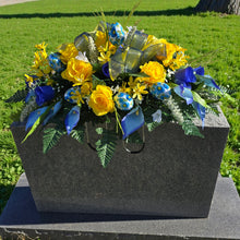 Load image into Gallery viewer, Spring Headstone Saddle has blue, yellow, & cream faux silk rose and calla lily grave flowers with floral print Easter eggs and ribbon.