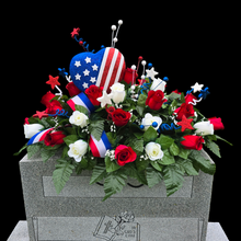 Load image into Gallery viewer, This headstone saddle is a patriotic cemetery decoration with grave flowers including red & cream roses and large American flag heart.