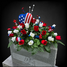 Load image into Gallery viewer, This headstone saddle is a patriotic cemetery decoration with grave flowers including red & cream roses and large American flag heart.
