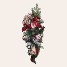 Load image into Gallery viewer, This is a teardrop door hanger that is a festive swag for Christmas season. It has berries, pinecone, snowballs, cute snowman, and a bow.
