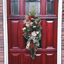 Load image into Gallery viewer, This is a teardrop door hanger that is a festive swag for Christmas season. It has berries, pinecone, snowballs, cute snowman, and a bow.
