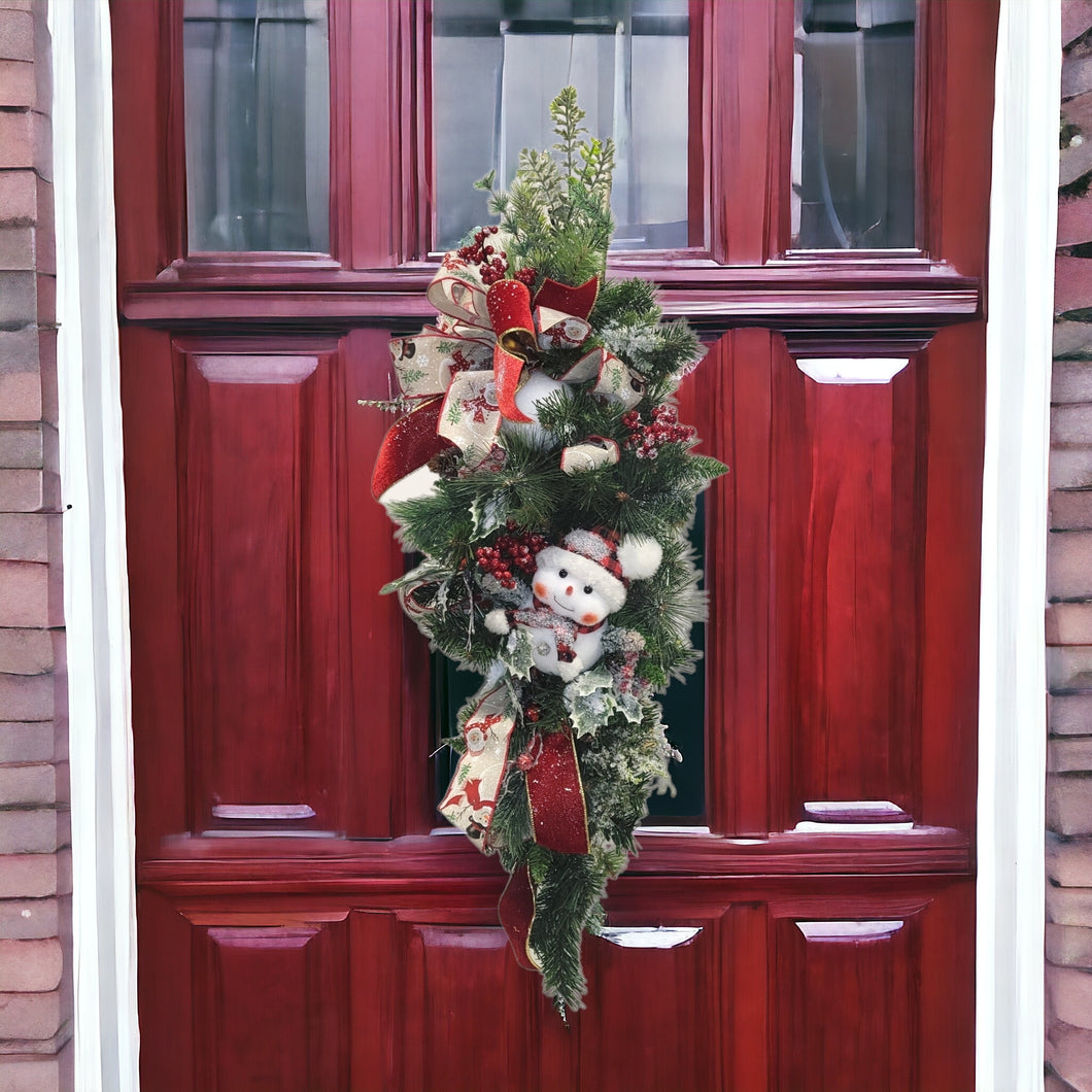 This is a teardrop door hanger that is a festive swag for Christmas season. It has berries, pinecone, snowballs, cute snowman, and a bow.