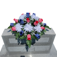 Load image into Gallery viewer, This Stars and Stripes Rosebud cemetery saddle decoration has grave flowers including stars and stripe rosebuds and White Spider Mums.
